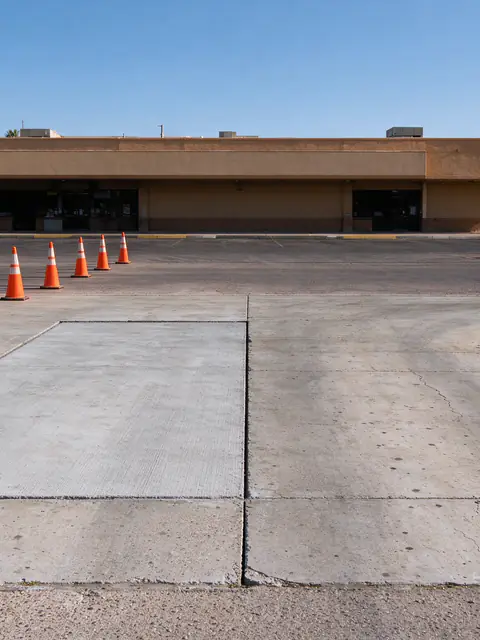Commercial concrete entrance driveway in Tempe with one lane-width panel replaced and traffic cones set out