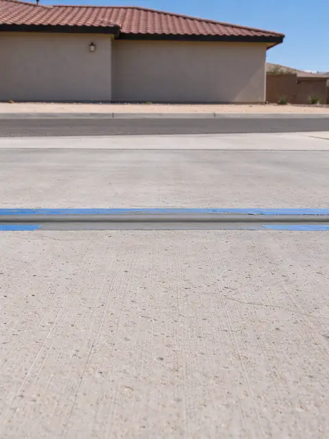 Driveway expansion joint at the sidewalk in Chandler freshly filled with gray sealant between strips of tape